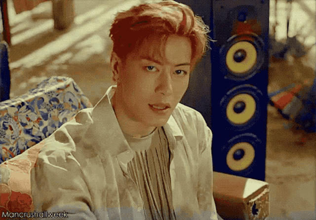 a man with red hair is sitting on a couch in front of a speaker with the words mancrushallweek written below him
