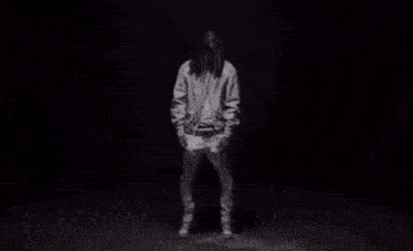 a man with dreadlocks is standing in front of a lightning storm .