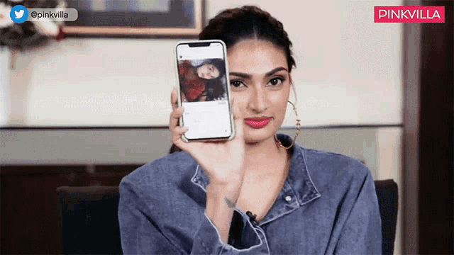 a woman holding a cell phone in front of her face with pinkvilla written on the bottom right