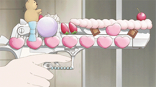 a person is pointing at a gun decorated with hearts and berries