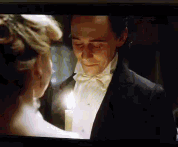 a man in a tuxedo and bow tie is standing next to a woman in a white dress .