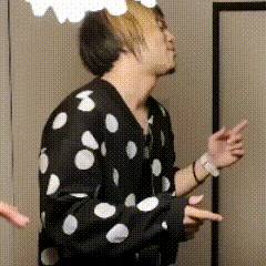a man in a black and white polka dot shirt is pointing at something