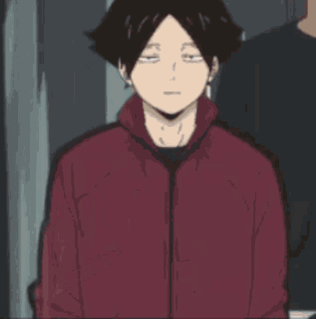 a young man in a red jacket is standing next to a group of people .