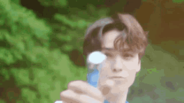 a young man is holding a soap bubble in his hand in front of his face .