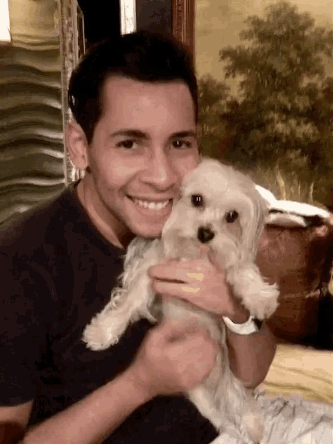 a man holding a small white dog in his arms