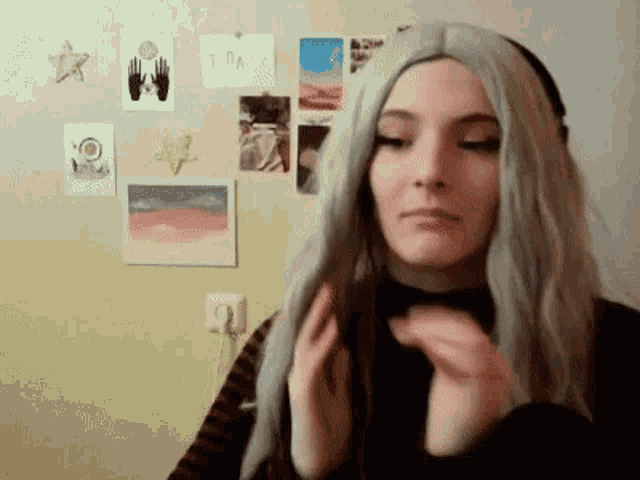 a woman wearing a wig and headphones is standing in front of a wall .