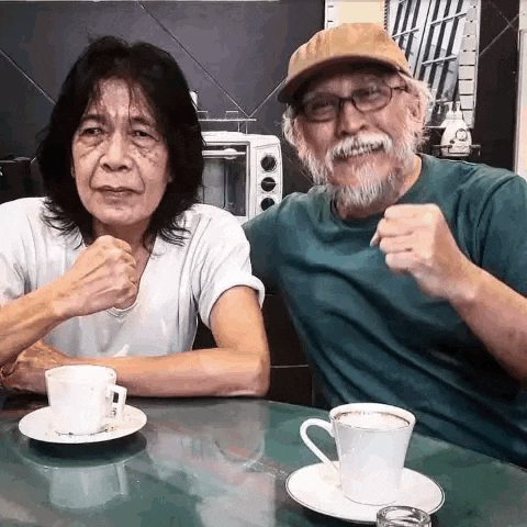 a man and a woman are sitting at a table with two cups of coffee .