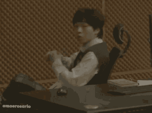 a man sitting at a desk with the word amaerosario on the bottom left