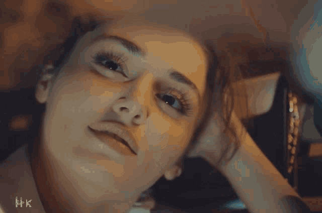 a close up of a woman 's face with hk written on the bottom right