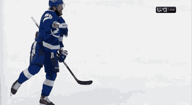 a hockey player is holding a puck in front of a usa live screen
