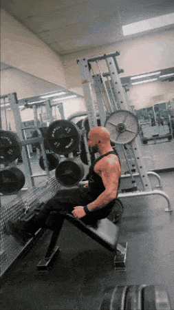 a man is sitting on a bench in a gym with a machine that says ' xtreme ' on it