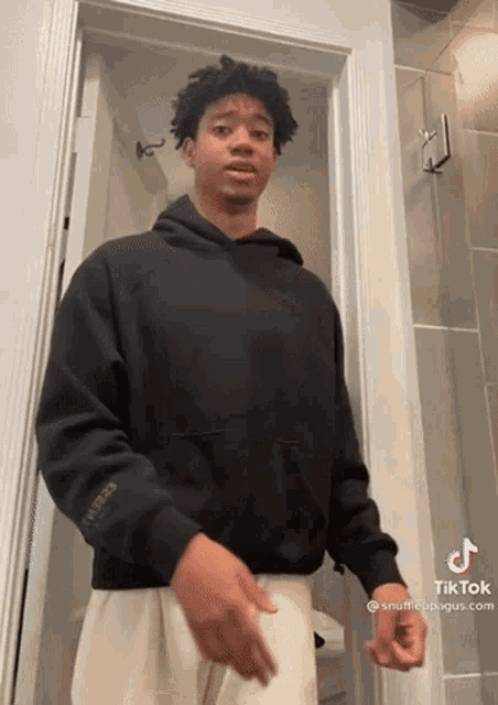 a man in a black hoodie is standing in a doorway with a tiktok watermark