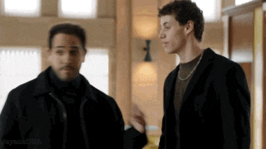 two men are standing next to each other in a room talking .