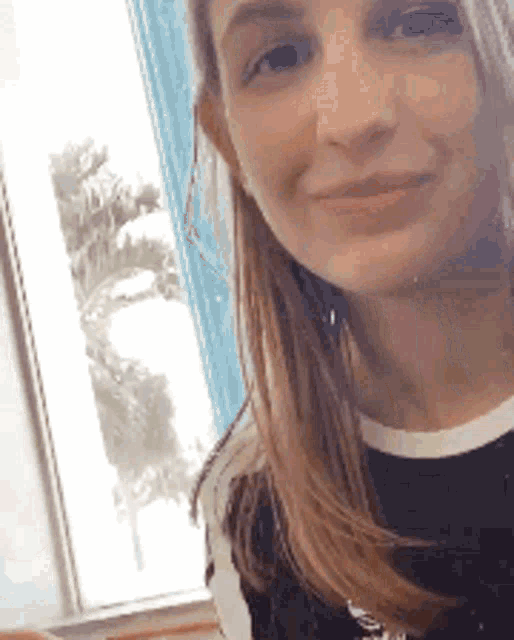 a woman is smiling in front of a window .