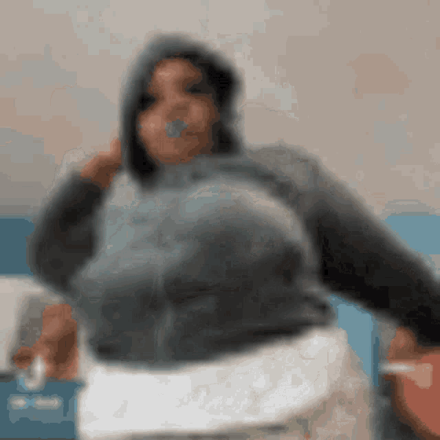a woman with very large breasts is wearing a hoodie and holding a cigarette .