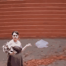 a woman in a purple dress is holding a bouquet of flowers in front of a brick wall