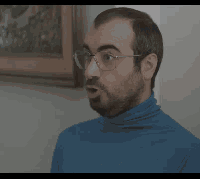 a man wearing glasses and a blue turtleneck has a question in hebrew on the screen