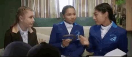a group of girls are sitting on a couch talking to each other .