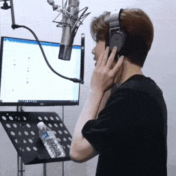a man wearing headphones is singing into a microphone in front of a dell computer