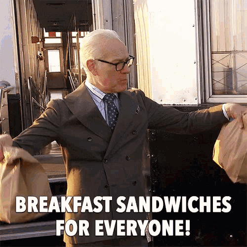 a man in a suit holding a bag of breakfast sandwiches for everyone