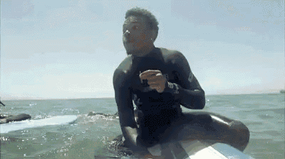 a man in a wetsuit is riding a surfboard in the ocean .