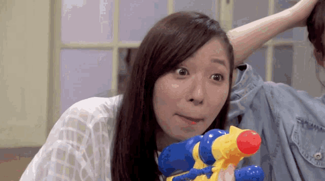 a woman is holding a water gun and making a face