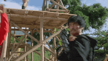 a man in a black jacket is standing on a wooden scaffolding