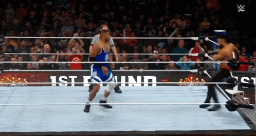 a wrestler in a blue shirt stands in the ring with a sign that says 1st is ind