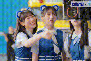 three girls in blue uniforms are standing next to each other and one of them is pointing at something .