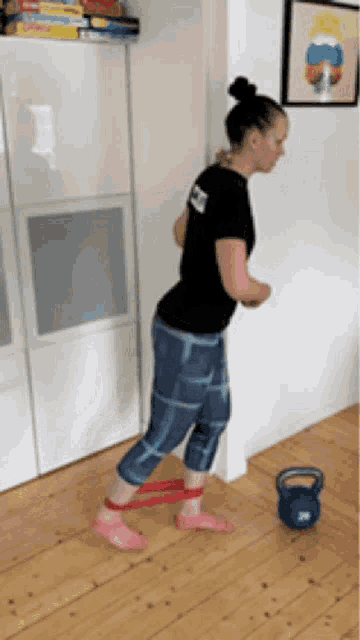 a woman is doing exercises with a resistance band on her feet in a living room .