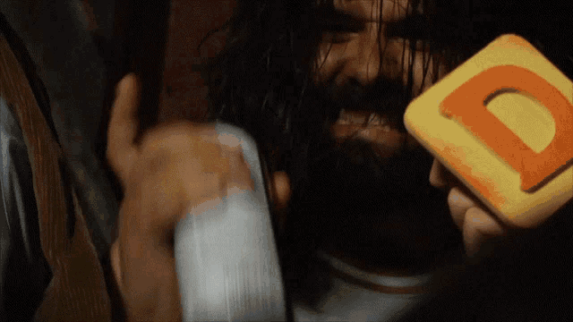 a man with a beard is holding a yellow and orange letter d
