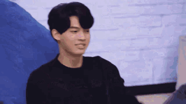 a young man in a black shirt is sitting in front of a blue bean bag chair .