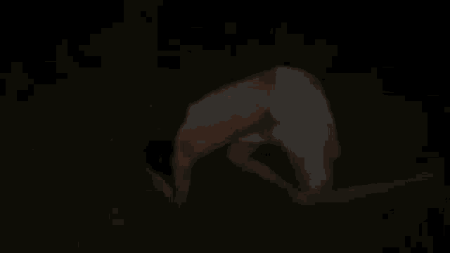 a shirtless man is crawling on the ground at night .