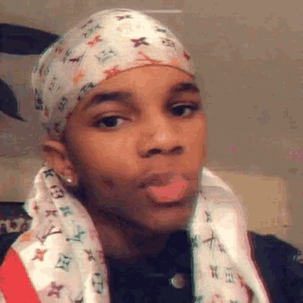 a young man wearing a head scarf and a louis vuitton scarf around his head .