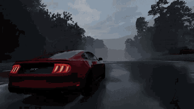 a red mustang gt is driving on a wet road