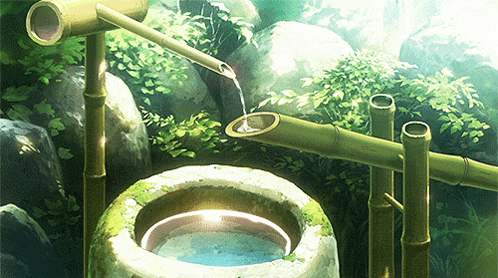 a bamboo fountain is pouring water into a bowl