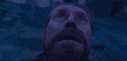 a close up of a man 's face with a beard looking up at the sky .