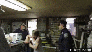 a group of people are standing in a room with a police officer in the middle .