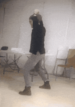 a man wearing a hat is dancing in a room
