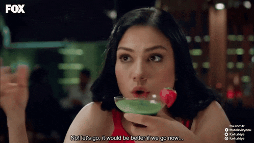 a woman in a red dress is drinking from a martini glass with a strawberry in it and says no let 's go