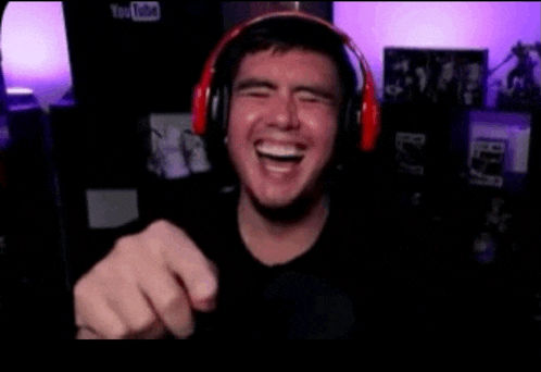 a man wearing headphones is laughing and pointing
