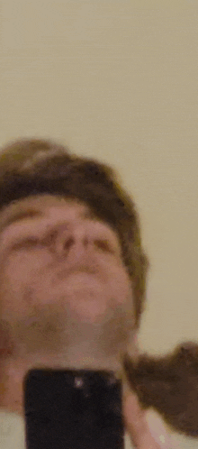 a man is taking a selfie with a cell phone in front of a mirror .