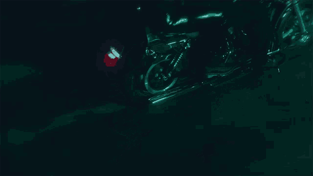 a person is riding a motorcycle in the dark with a green light behind them