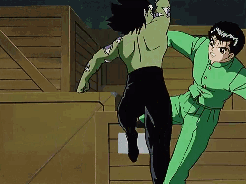 a man in a green shirt is kicking another man in a black shirt