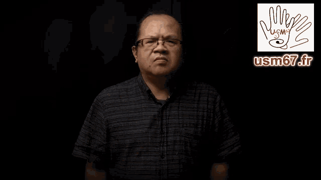a man wearing glasses says merci a toi aussi in sign language