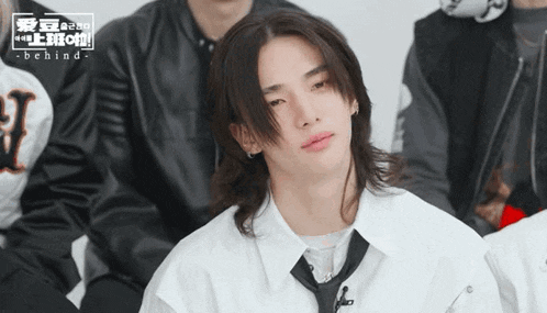 a man with long hair wearing a white shirt and black tie