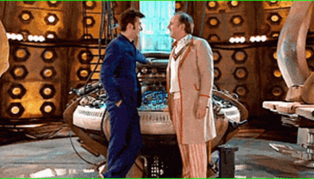 two men standing next to each other in front of a large machine