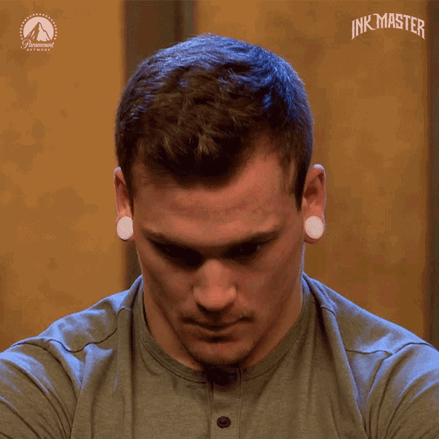 a man with ear plugs and a shirt that says ' ink master ' on the bottom