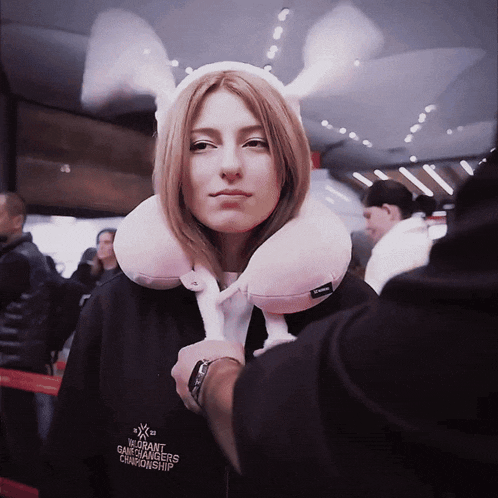 a woman wearing bunny ears and a neck pillow has a shirt that says world grand champions championship on it
