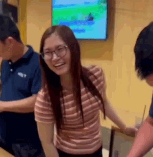 a woman wearing glasses is smiling while standing next to a man in a room .